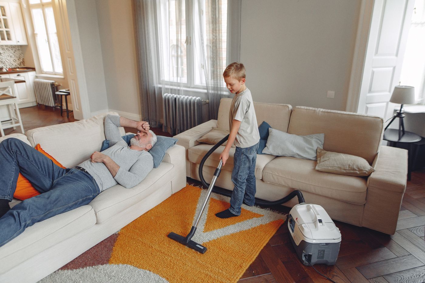 A living room being vacuumed while the family relaxes on the sofa